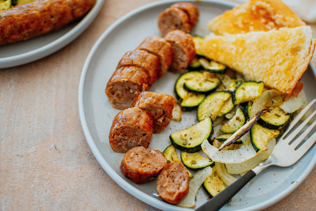 italian sausage zucchini, onion, and garlic bread on a plate