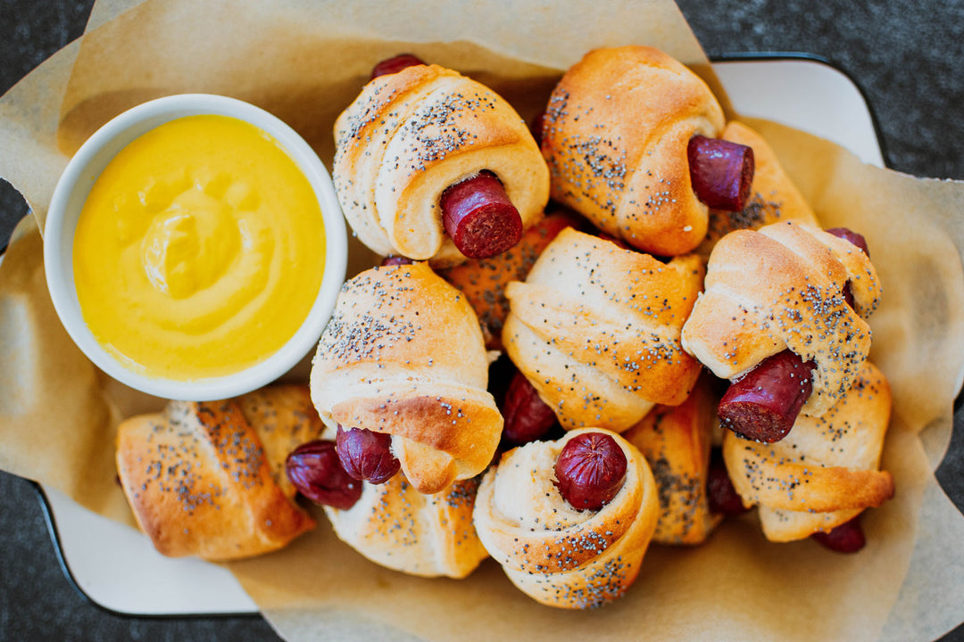 pigs in blanket in a basket with a side of mustard