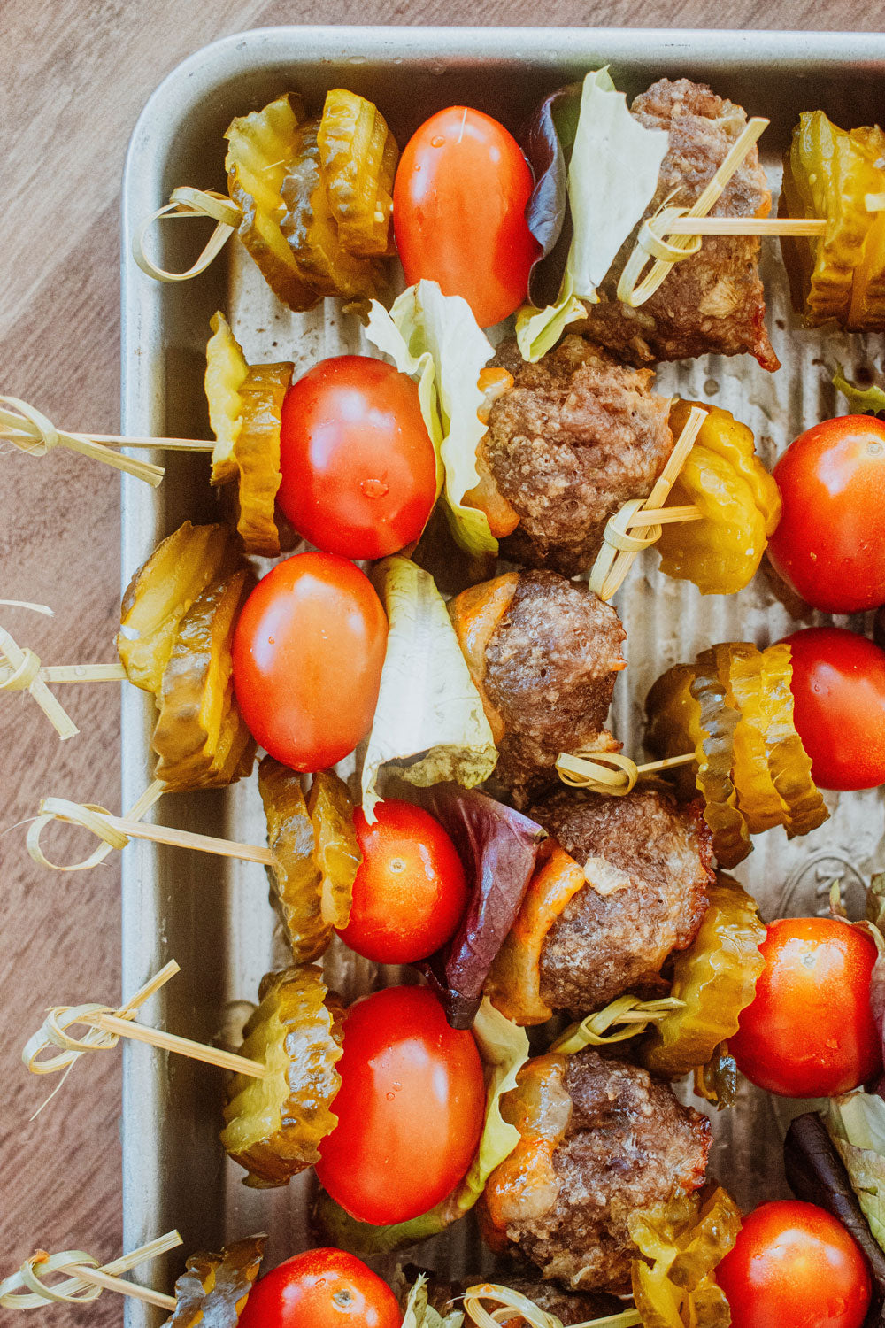 cheeseburger meatballs on skewers with lettuce, tomato and pickles