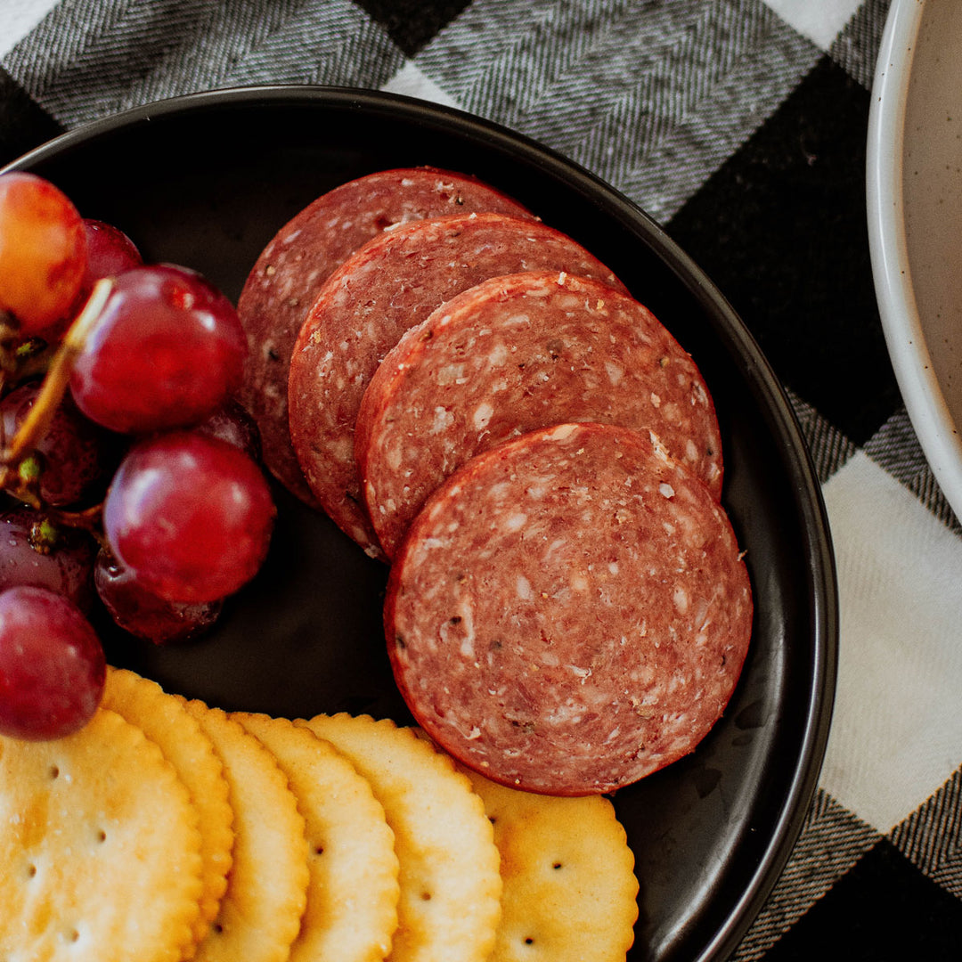 summer sausage on a plate with crackers and grapes